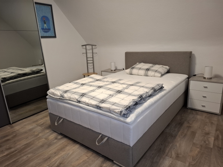 Schlafzimmer mit Bett, Nachttischen, einem Spiegelschrank.