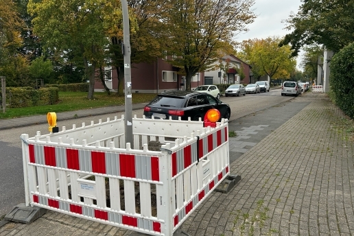 Husemannstraße in Waltrop, im Vordergrund Baustellenabsperrungen, ein Auto befährt die Straße, links uns rechts parken weitere Autos.