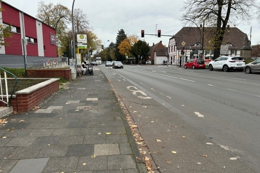 Bushaltestelle "Rathaus Waltrop" an der Wilhelmstraße an der Kreuzung Hochstraße/Münsterstraße, links ist das "Yahoo" zu sehen, am Straßenrand parken Autos, auf der Straße sind Fahrzeuge unterwegs.