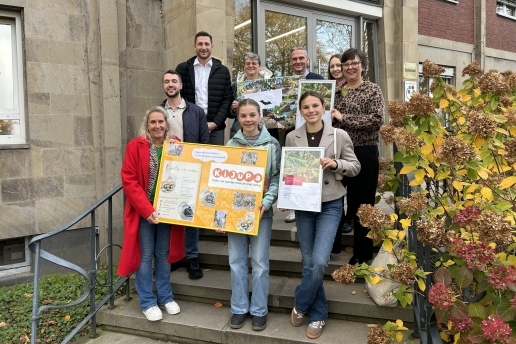Neun Personen stehen anlässlich der Klimaschutzpreis-Vergabe auf den Treppenstufen vor dem Rathaus und halten Plakate und Urkunden in der Hand.
