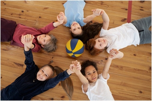 Symbolbild: Schulsport in der Sporthalle. Kinder spielen mit einem Ball.