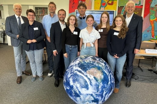 Zehn Personen stehen in einem Raum in der Waltroper Realschule, im Vordergrund eine aufblasbare Erdkugel.
