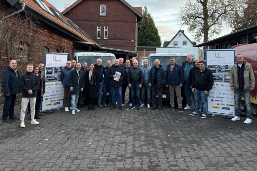 Knapp 25 Personen stehen auf dem Hof der Waltroper Parkfesthalle mit zwei Bannern vor zwei Transportern mit Werbe-Folierung. 