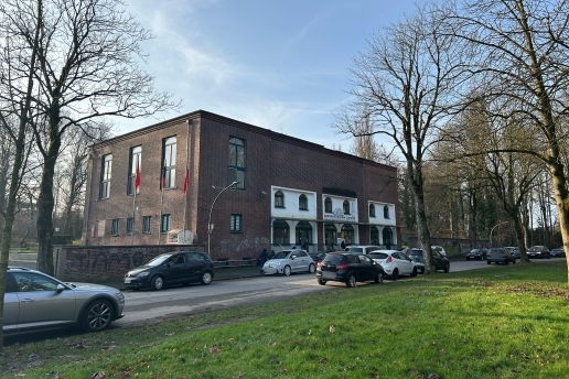Das Gebäude der DITIB-Moschee an der Sydowstraße, umgeben von Bäumen, im Vordergrund parken Autos an einer Straße. 