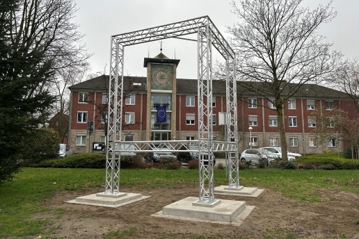 Eine dreieckige Werbeanlage aus Metall steht auf der Wiese vor dem Waltroper Rathaus.  