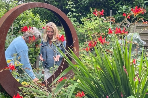 Zwei Frauen stehen in einem Garten, zu sehen ist ein großer Dekorations-Ring aus Cortenstahl. 