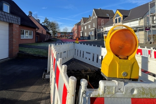 Blick in die Hilberstraße Richtung Feuer- und Rettungswache, rechts und links Häuser, im Vordergrund ein Baustellenbereich mit rot-weißen Warnbaken. 