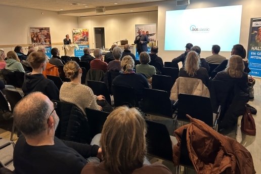 Jörg Baly steht bei der Auftaktveranstaltung Macherstadt vor den Zuschauerreihen und hält ein Mikro in der Hand.
