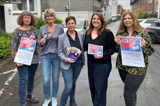 Fünf Frauen stehen mit  Plakaten und Flyern in einer Straße.