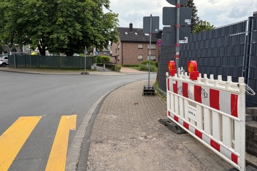 Baustellenzaun, Bürgersteig, Straßeneinmündung, Häuser