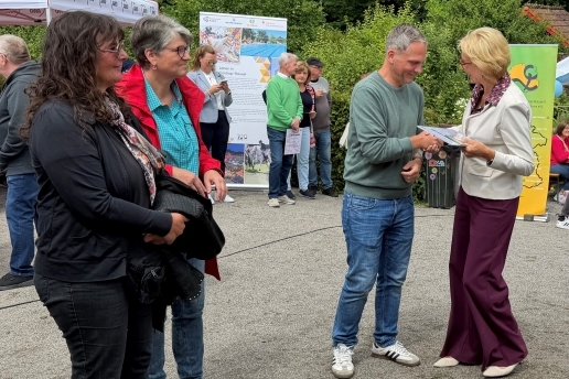 Ute Kölker gratuliert Manuel Kiese zum Erfolg beim Tag des Gartens. Mehrere Personen stehen im Hintergrund. 