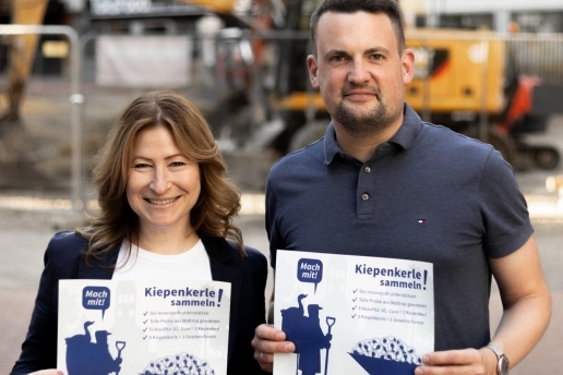 Ein Mann und eine Frau halten Plakate für die Aktion "Kiepenkerle" in den Händen.