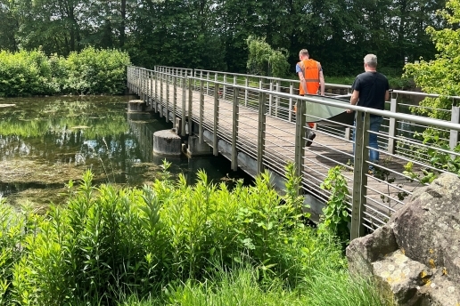 Zwei Männer gehen über eine Brücke, die über ein Kanal-Teilstück führt. 