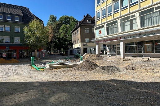 Blick auf die Baustelle am Platz von Gardelegen; hinten Häuserfassaden und Bäume, rechts ebenfalls eine Häuserfassade.