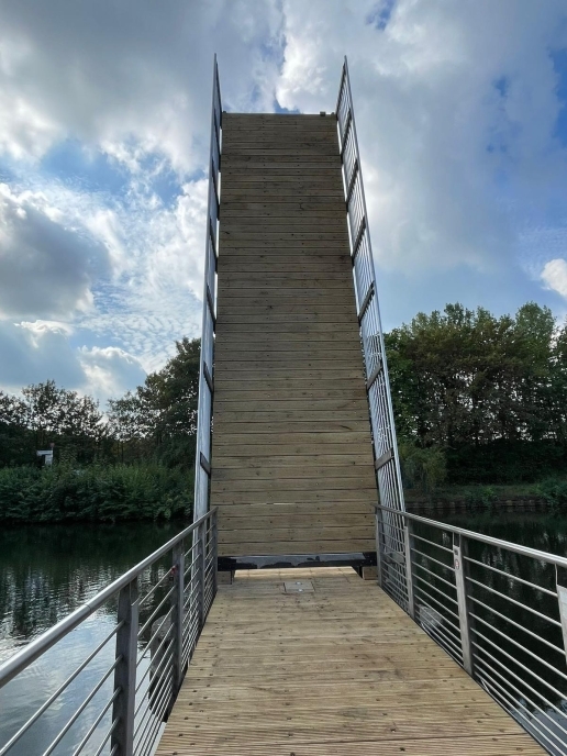 Eine hochgeklappte Brücke mit Holzbelag und Metall-Geländer.