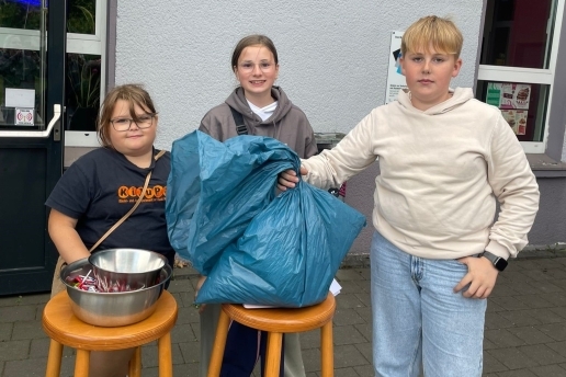 Eileen, Lili und Tom KiJuPa stehen mit einer Tüte voller gesammelter Zigarettenkippen am Yahoo. 