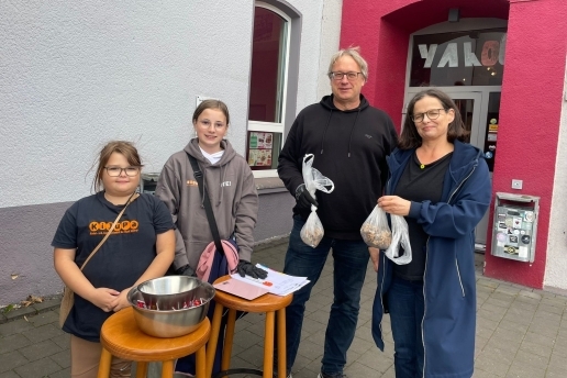 Eileen und Lili vom KiJuPa stehen mit Frank Vonnahme und Beate Stach (von links) von den Grünen mit Tüten voller Zigarettenstummel vor dem Yahoo.
