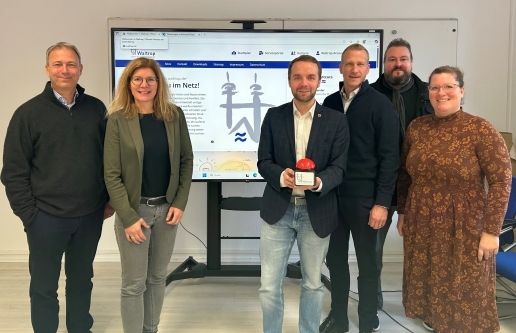 Sechs Personen stehen vor einem großen Monitor, auf dem die neue Website der Stadt Waltrop zu sehen ist. Von rechts: Ralf Schwarberg, Tamina Forytta, Marcel Mittelbach, Stefan Wilke, Rutger Koch, Andrea Middendorf.