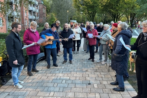Menschen stehen im Halbrund bei der Eröffnung des Stutenteichparks und halten Liedzettel in den Händen.