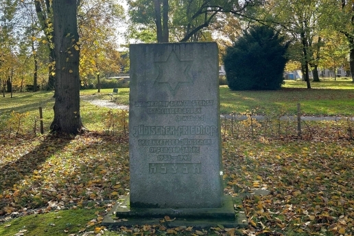 Gedenkstein auf dem Jüdischen Friedhof mit der Inschrift "Gedenket der jüdischen Opfer der Jahre 1933 - 1945" in Waltrop; im Hintergrund Wiese und Bäume. 