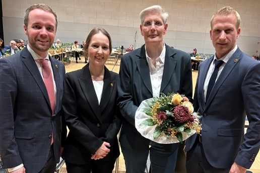 Vier Personen stehen in der Stadthalle Waltrop, eine davon hält einen Blumenstrauß in der Hand. 