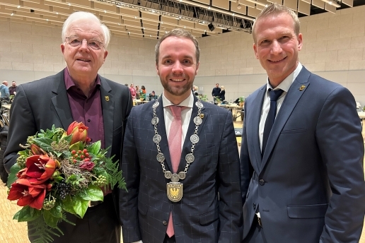 Der Altersvorsitzende des Stadtrats Waltrop Klaus Beie (links) steht neben Bürgermeister Marcel Mittelbach bei dessen Amtseinführung, rechts der Allgemeine Vertreter des Bürgermeisters, Stefan Wilke; im Hintergrund der Saal der Stadthalle.    