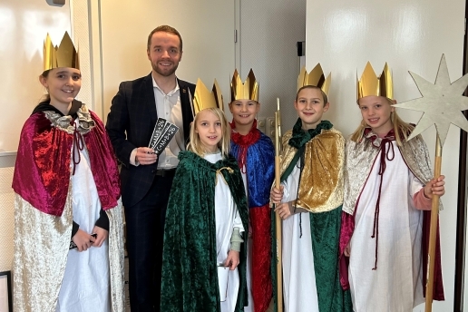 Fünf als Sternsinger gekleidete Kinder mit Sternen und Kronen stehen neben Bürgermeister Marcel Mittelbach. 