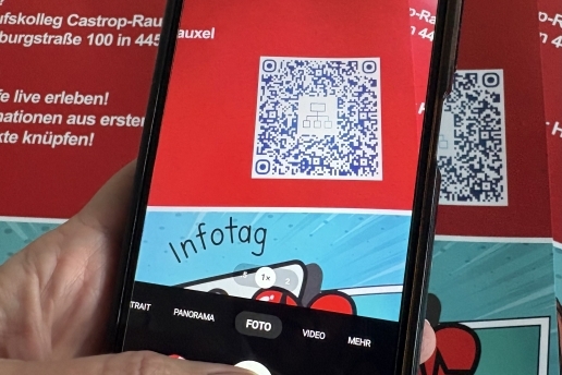 Eine Hand hält ein Handy, auf dem Display ist ein QR-Code und die Schrift "Infotag" zu sehen.