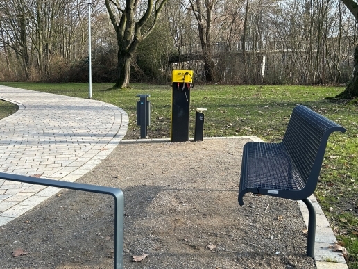 Eine Fahrradstation, eine Bank, im Vordergrund ein Fahrradbügel an einem Weg im Stutenteichpark