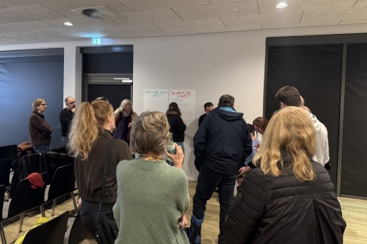 Menschen stehen in der Stadthalle vor Plakaten.