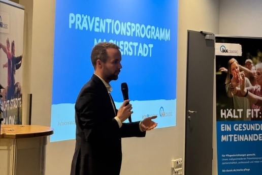 Bürgermeister Marcel Mittelbach hält bei der Auftaktveranstaltung Macherstadt im Foyer der Stadthalle Waltrop ein Mikro in der Hand, im Hintergrund eine Präsentation "Macherstadt".