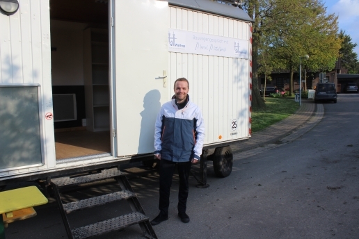 Ein Mann steht vor einem weißen Bauwagen mit geöffneter Tür, am Bauwagen ein Schild Bauwagengespräch Marcel Mittelbach (und Waltrop-Logo).