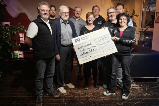 Eine Gruppe von Menschen steht mit einem symbolischen Spendenscheck in den Räumen des Jugendcafés Yahoo. 