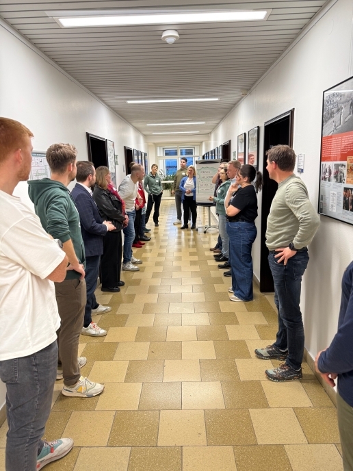 Mehrere Personen stehen auf dem Gang im Rathaus-Flur, im Hintergrund ein Flipchart.