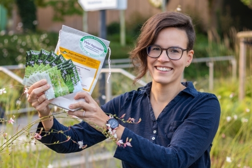 Eine Frau hält eine Packung mit Saatgut in die Kamera.