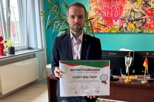 Bürgermeister Marcel Mittelbach hält eine Beitrittsurkunde zum Netzwerk "#sicherimdienst" in den Händen.