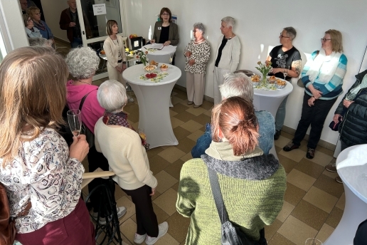 Mehrere Personen stehen im Treppenflur des Rathauses, manche an Stehtischen. 