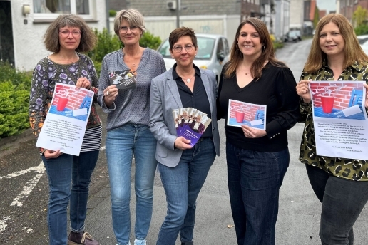Fünf Frauen stehen mit  Plakaten und Flyern in einer Straße.