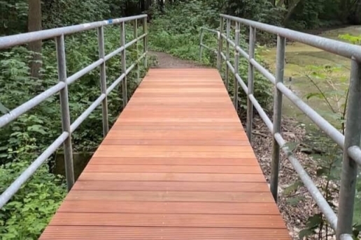 Eine Brücke mit Geländer an einem Teich.