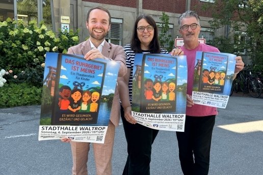 Drei Personen halten vor dem Rathaus Waltrop Plakate für das Musiktheaterstück "Das Ruhrgebiet ist MEINS" in die Höhe. 
