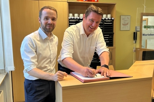 Zwei Männer in weißen Hemden unterzeichnen ein Schreiben.