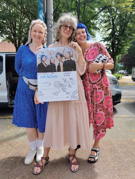 Drei Frauen mit einem Plakat. 