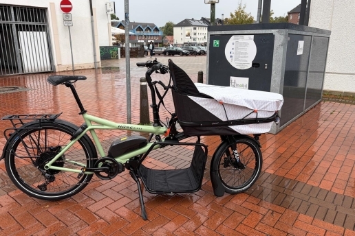 Ein lindgrünes Lastenrad vor einer Fahrradgarage am Platz hinter der Stadthalle Waltrop.